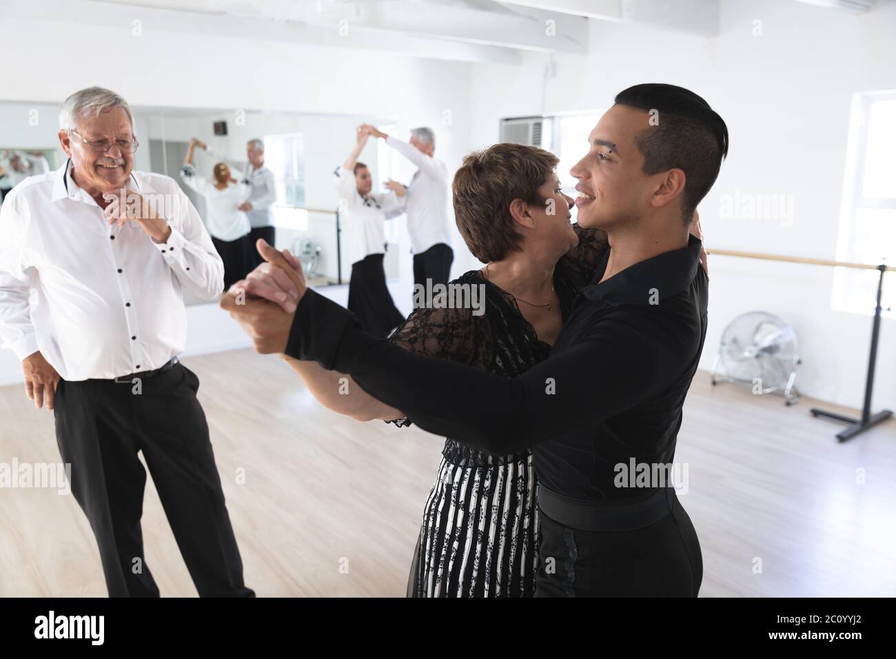 Mixed race dance teacher helping his ballroom dancing class Stock Photo