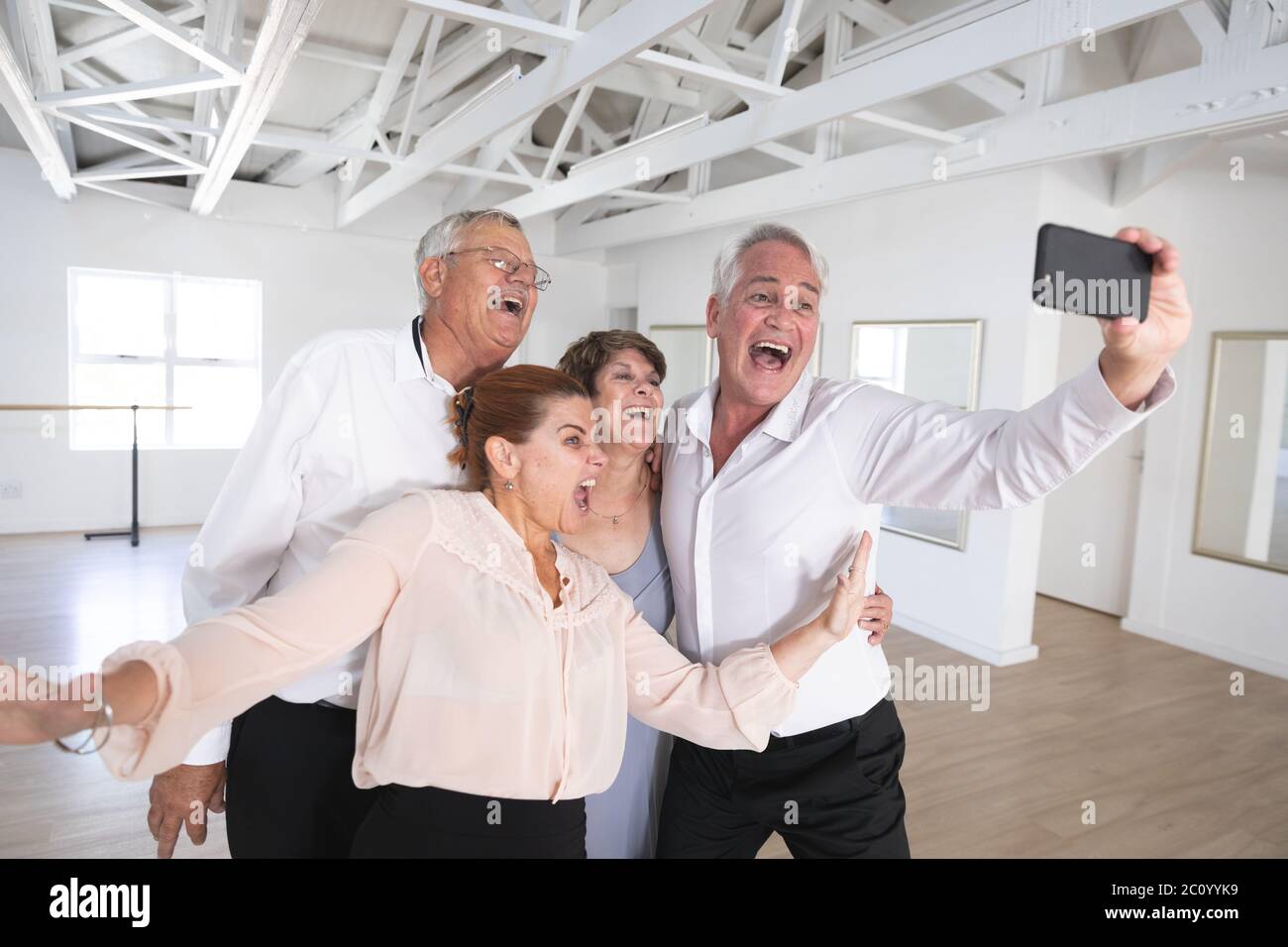 Happy Caucasian senior couples taking selfies during ballroom dancing Stock Photo