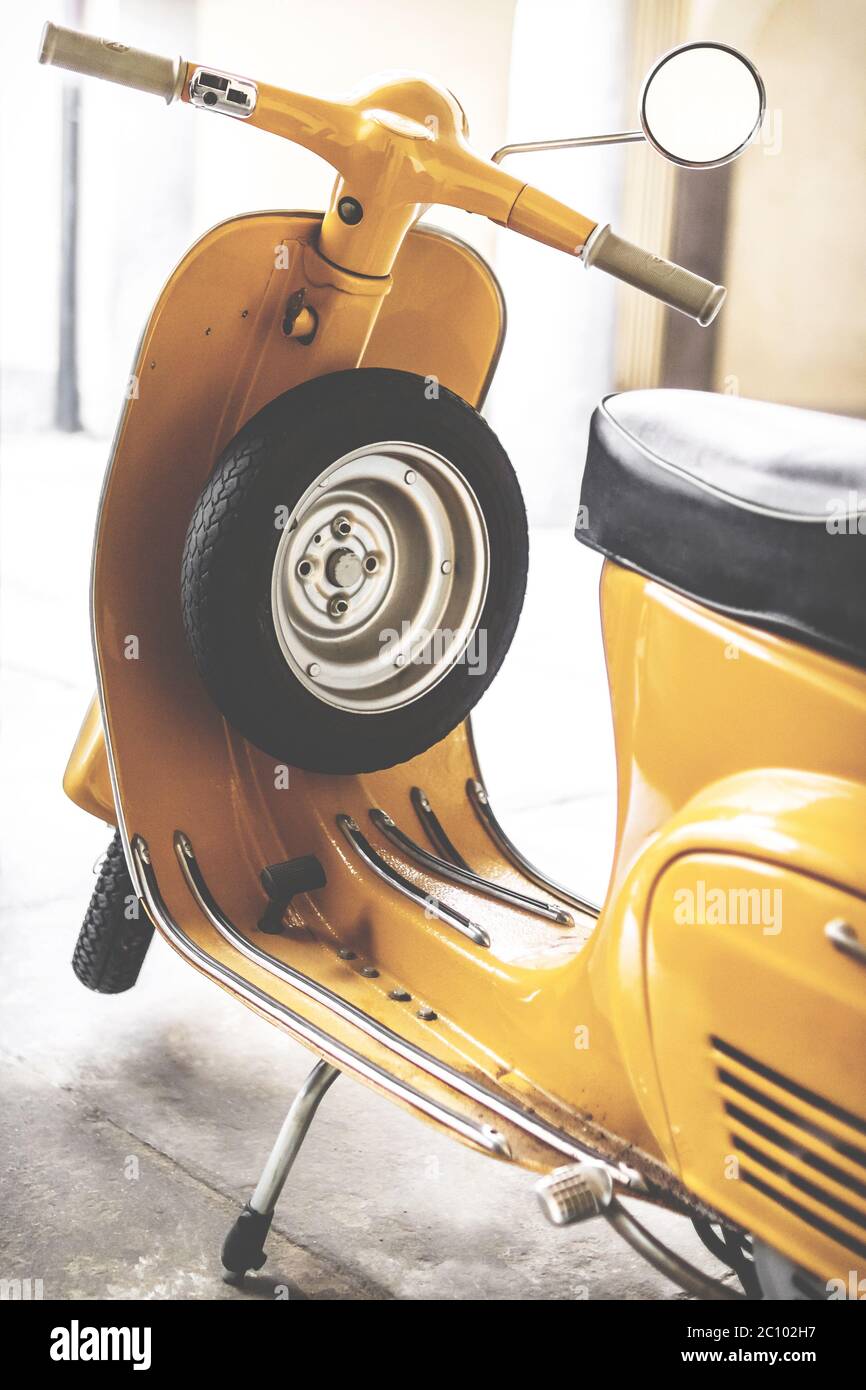 Vespa scooter with yellow paint. Vespa is an Italian brand of scooter manufactured by Piaggio. The iconic Italian designed scooter. Retro style photo. Stock Photo