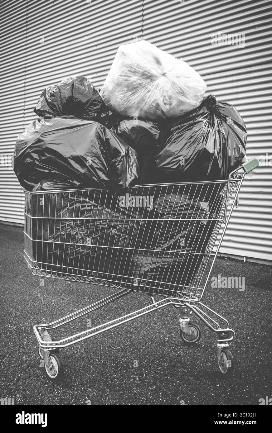 Shopping cart with a pile of rubbish inside. Pollution, recycle