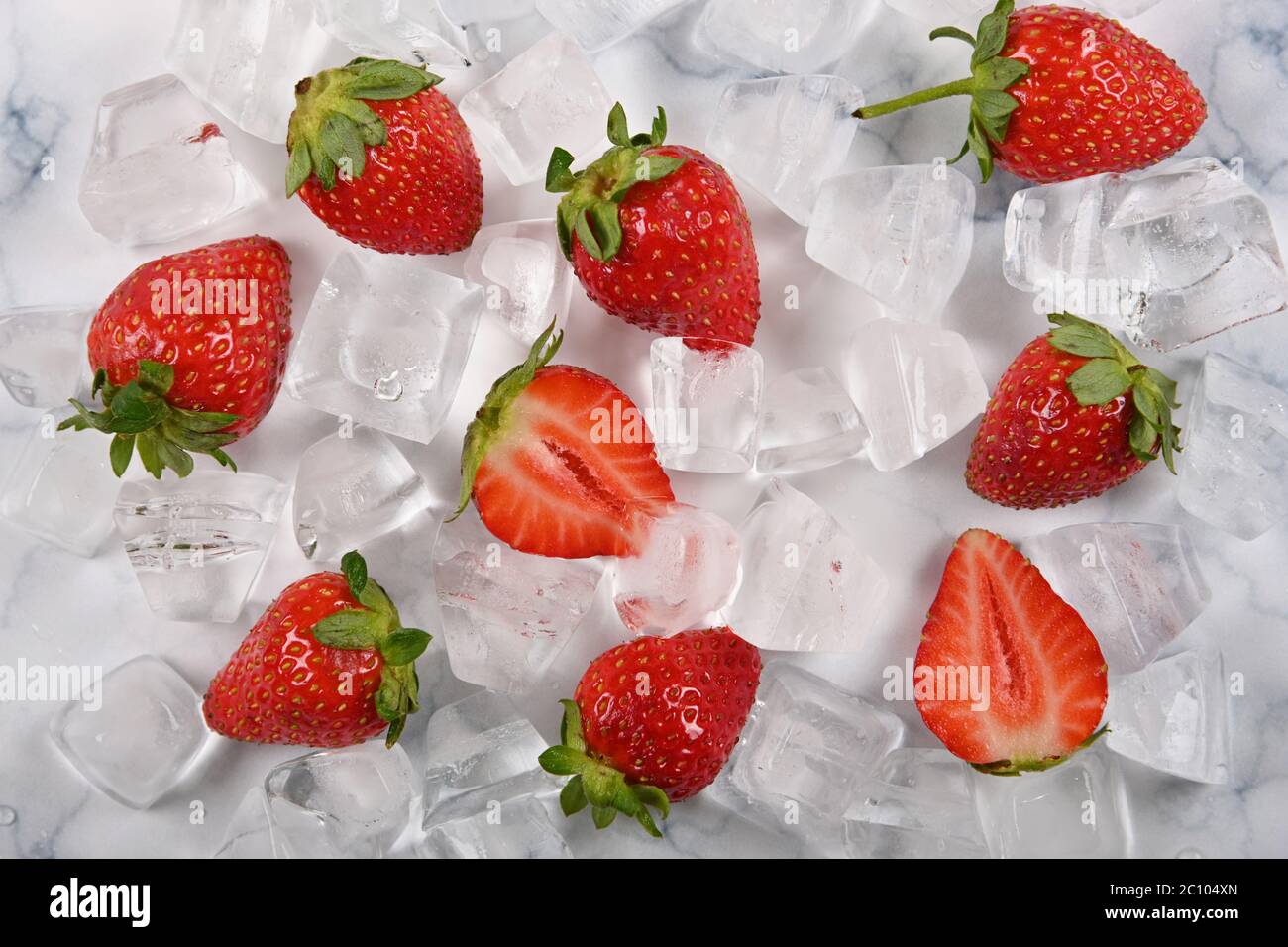 Close up fresh red ripe strawberries and ice cubes on table, el;evated high angle view, directly above Stock Photo