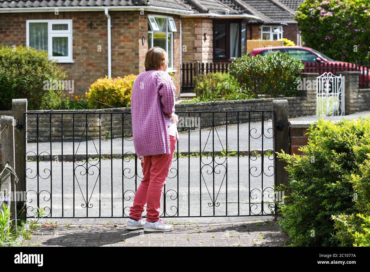 woman standing at her front gate during the covid-19 pandemic Stock Photo