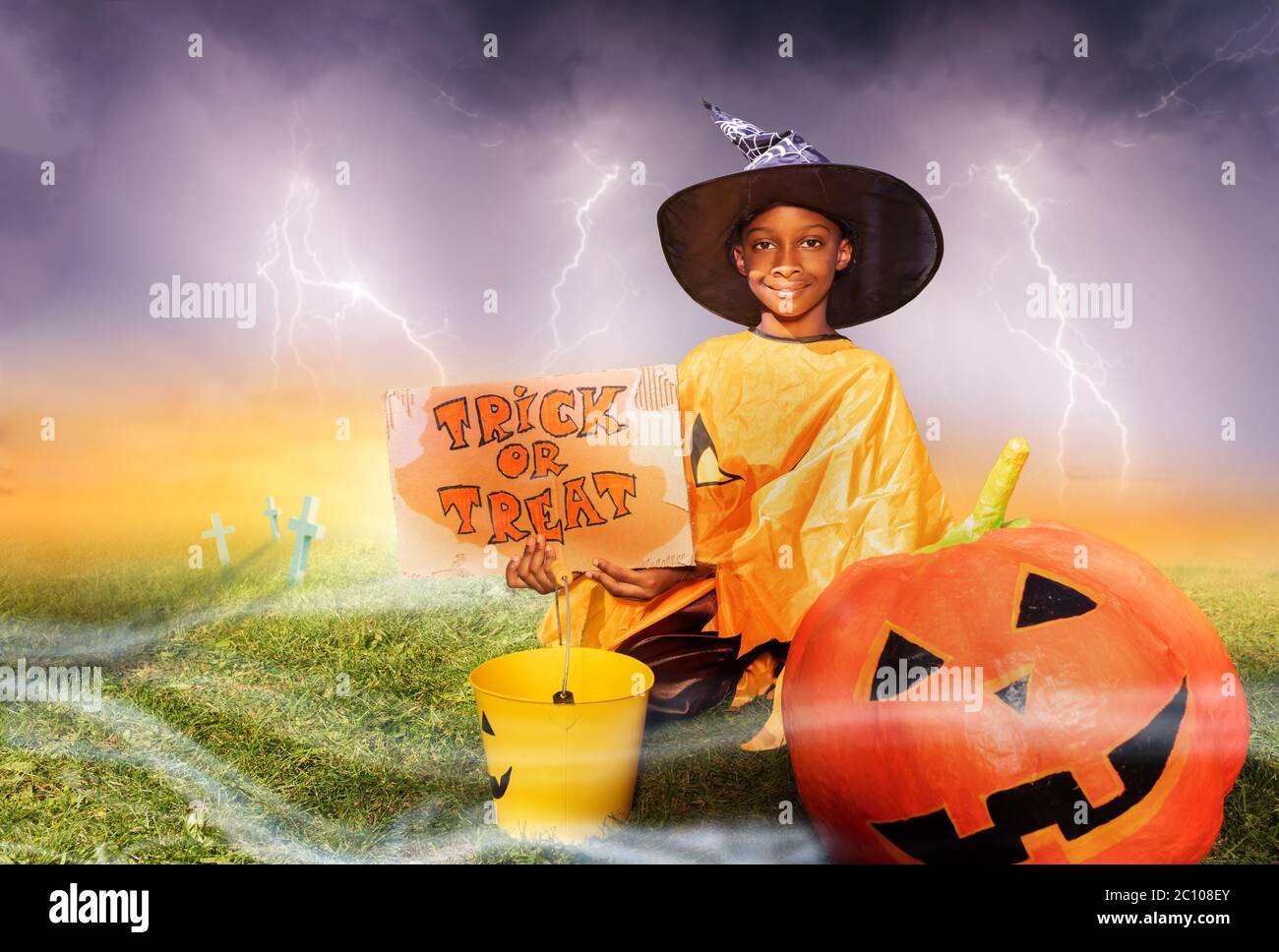 Cute handsome little black boy on Halloween sit with pumpkin and trick