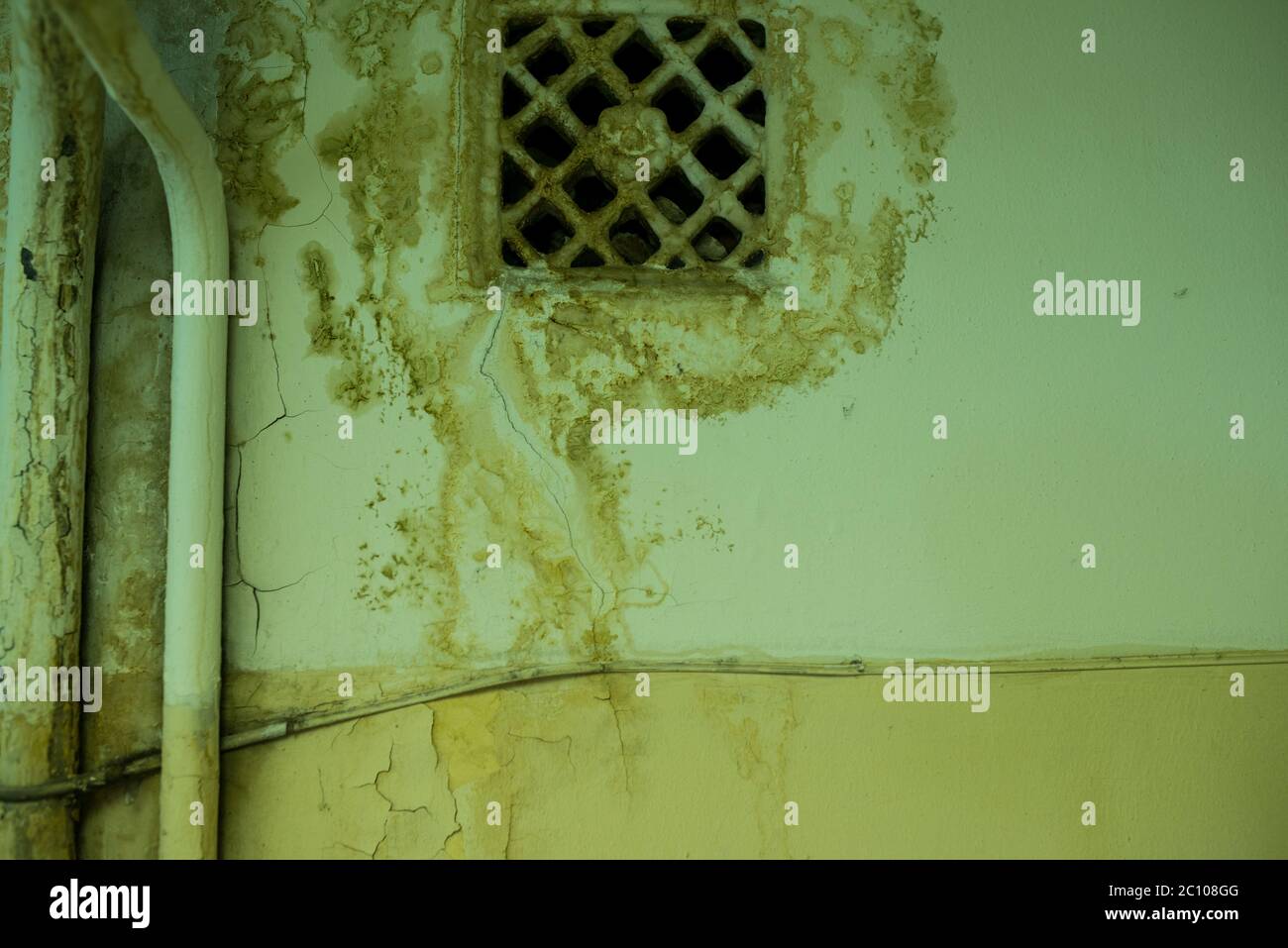 old ventilating lattice and two pipes on the wall with dirty streaked Stock Photo