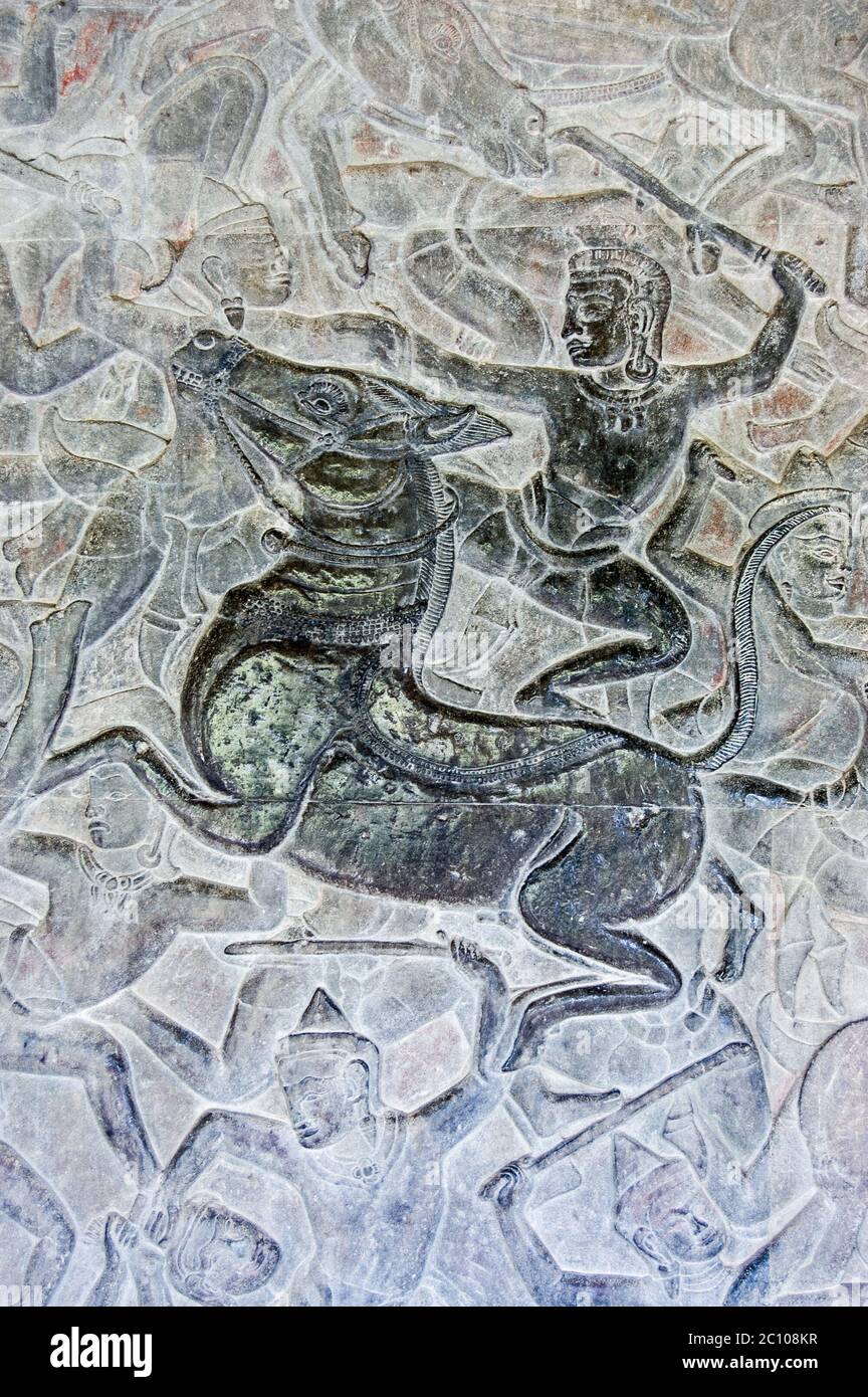 Ancient Khmer bas relief carving showing a Hindu god riding a horse into battle. Wall of Angkor Wat temple, Siem Reap, Cambodia. Stock Photo