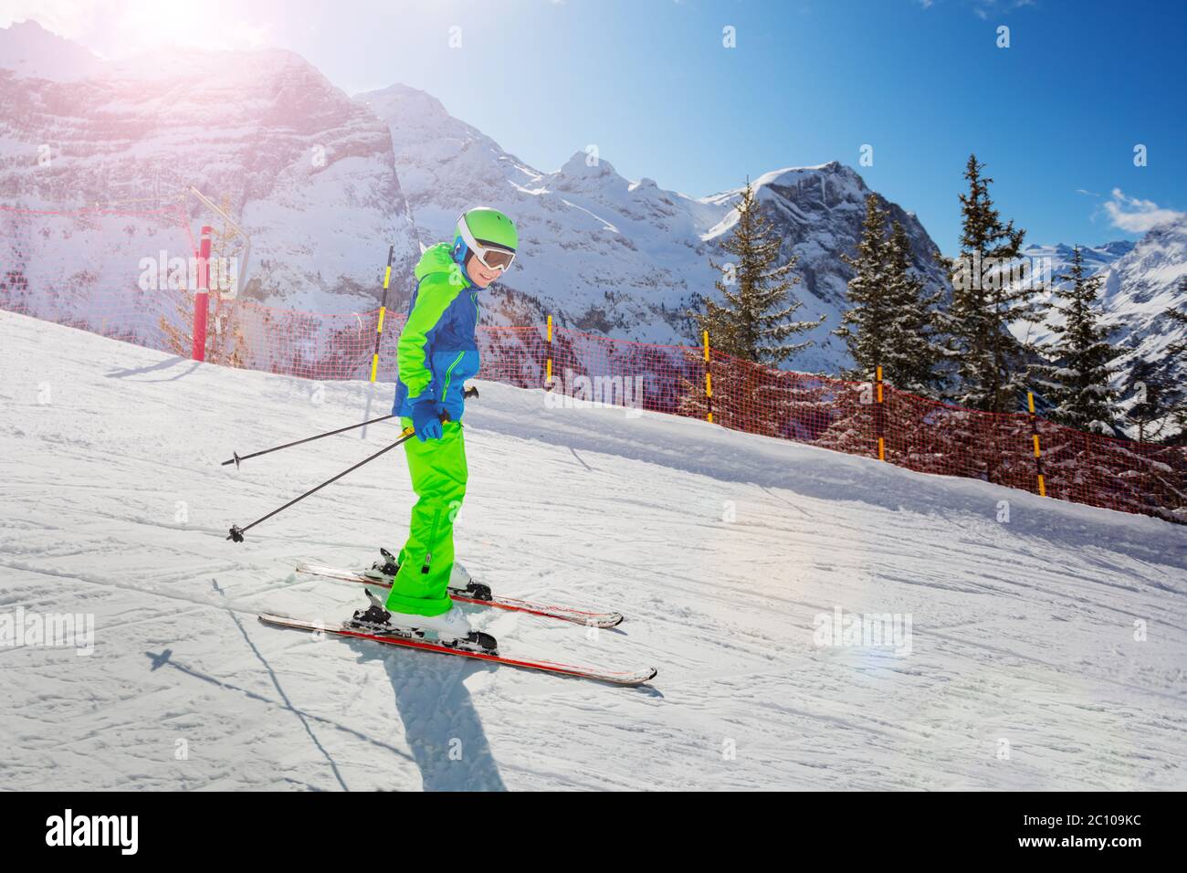 Cute 10 years old boy skier racing fast down the slope in bright green