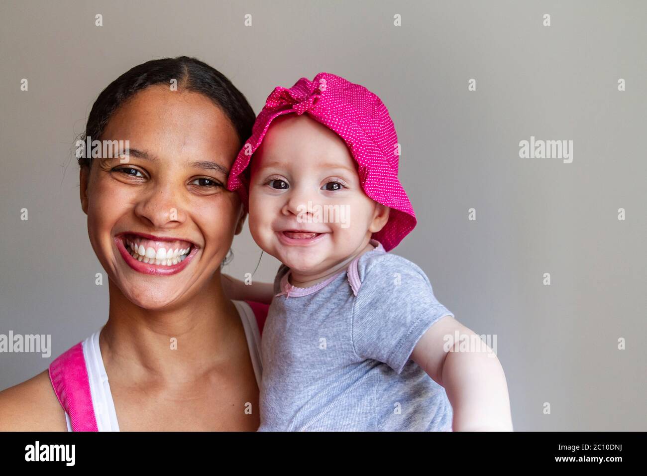 Black mother and her daughter white and redhead in contrast with neutral background Stock Photo