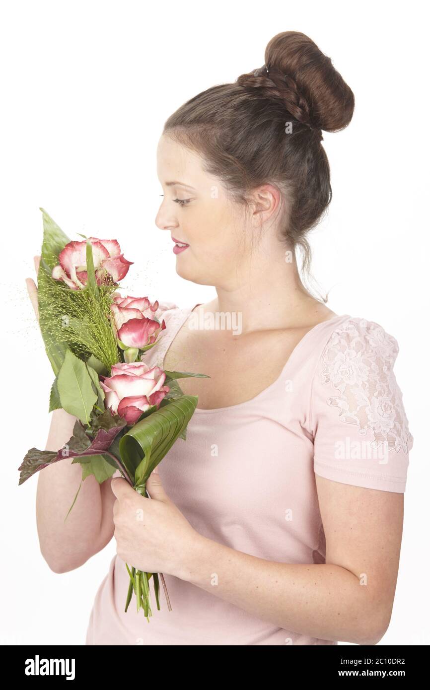 Young brunette woman in a chignon holding a bouquet of flowers (roses) Stock Photo