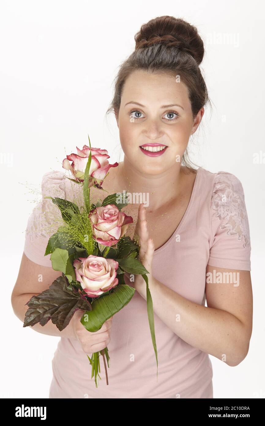 Young brunette woman in a chignon holding a bouquet of flowers (roses) Stock Photo