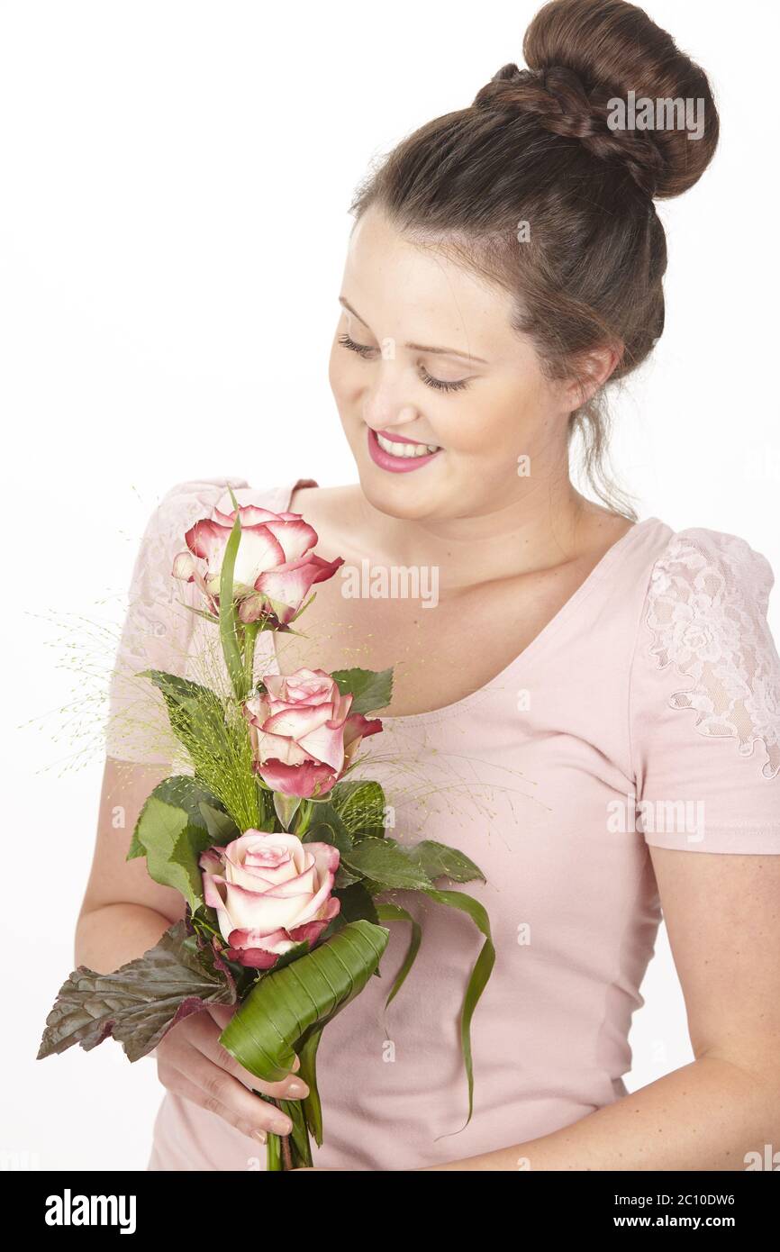 Young brunette woman in a chignon holding a bouquet of flowers (roses) Stock Photo
