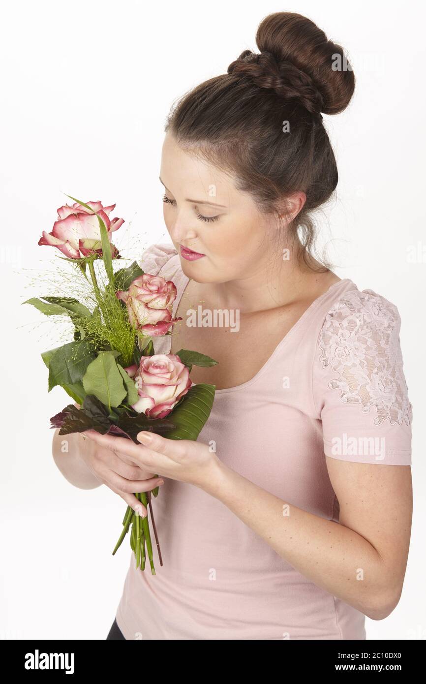 Young brunette woman in a chignon holding a bouquet of flowers (roses) Stock Photo