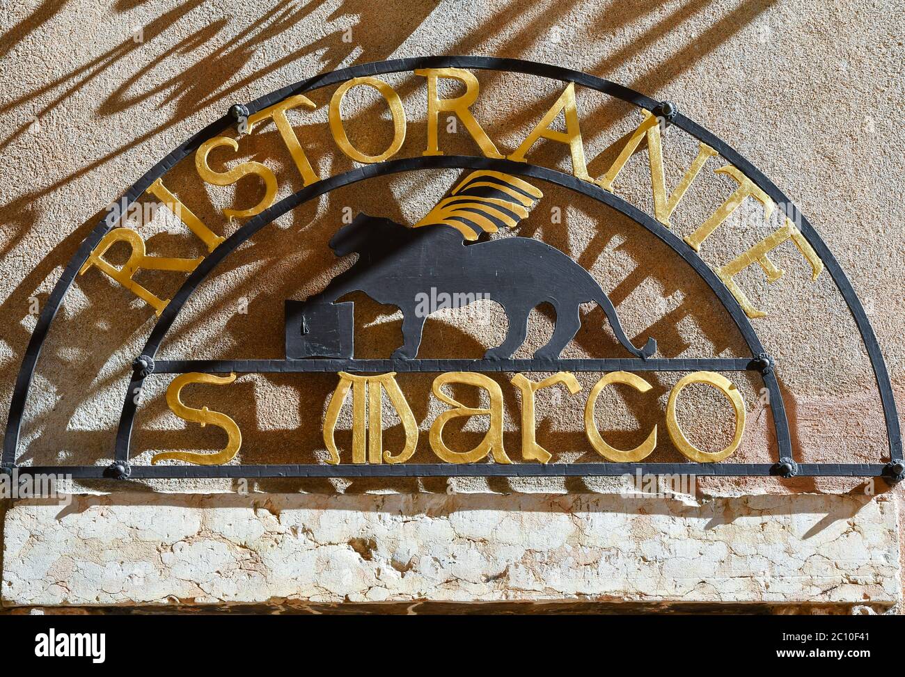 Close-up of the metal sign of a restaurant with the winged Lion of St Mark, symbol of the city of Venice on an old wall, Lazise, Verona, Veneto, Italy Stock Photo