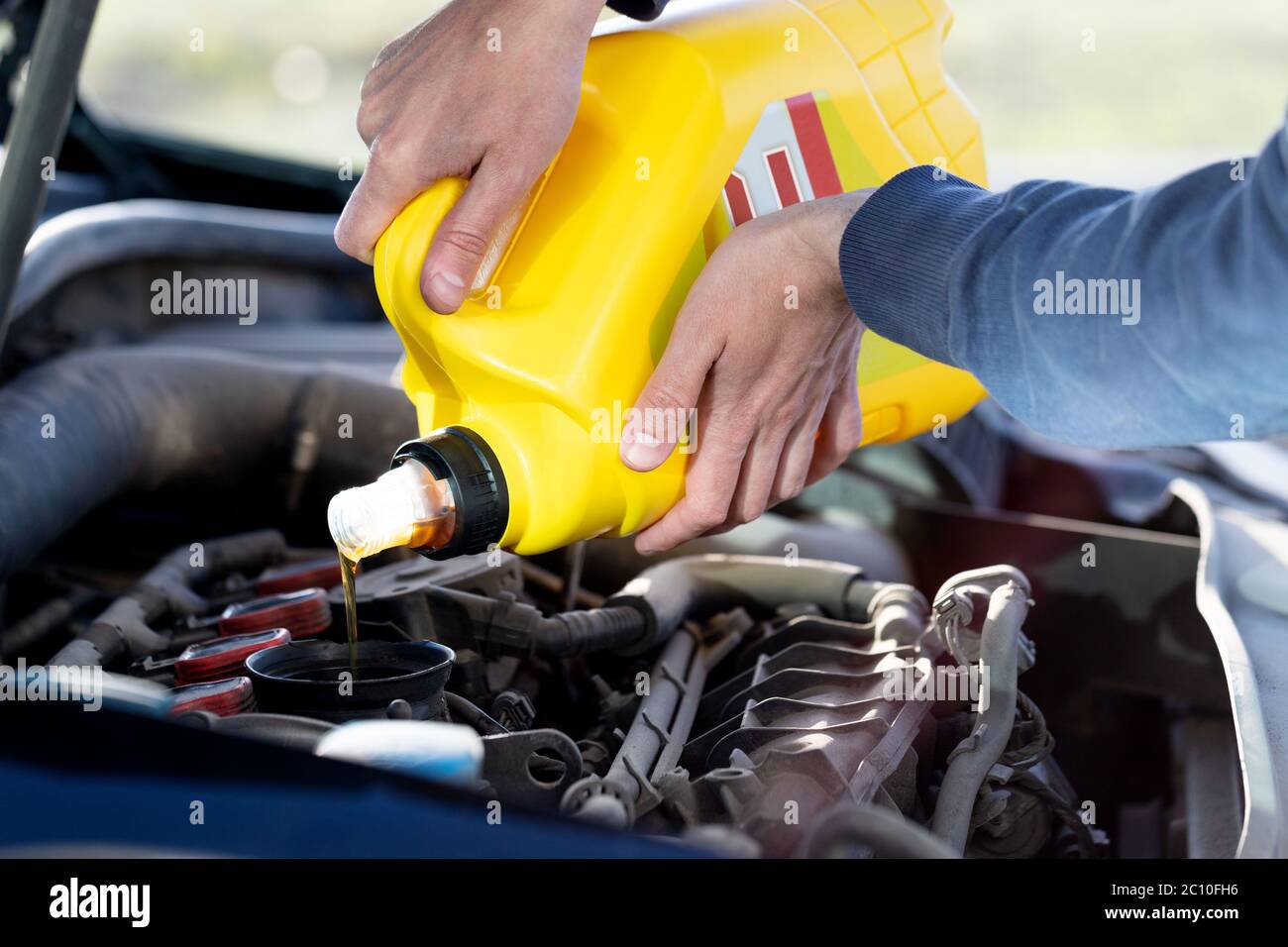 Man driver pouring and refueling oil quality into the engine motor car