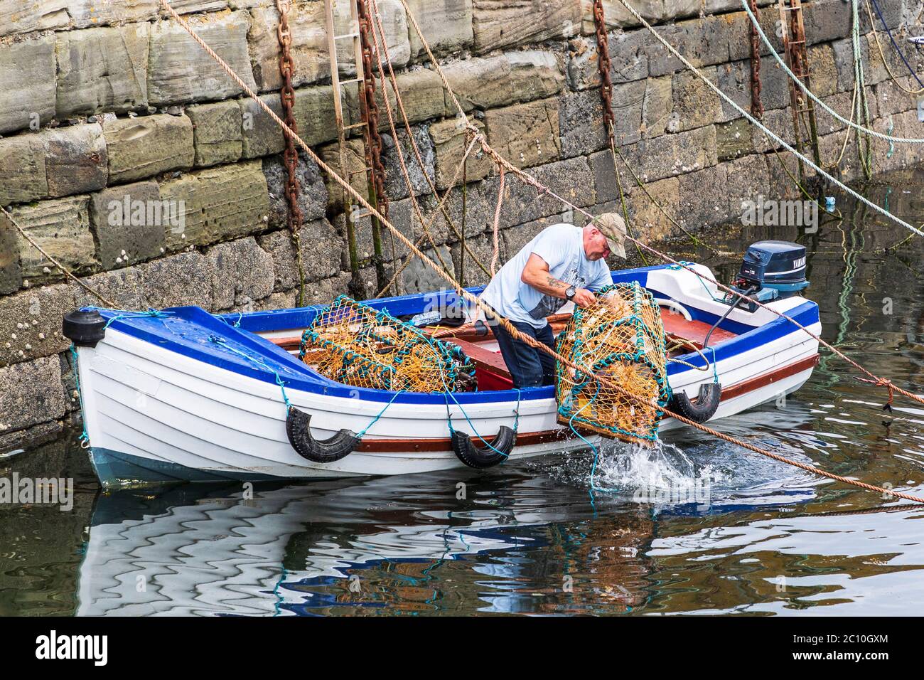 Fisherman preparing lobster pots on the harbourside at Dunure harbour, Ayrshire, Scotland, UK Stock Photo