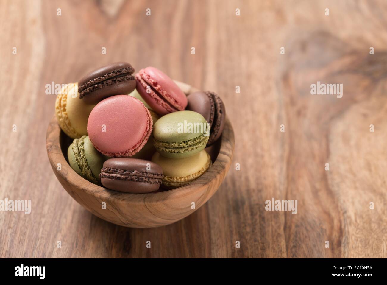 Various french macarons in olive wood bowl with copy space Stock Photo