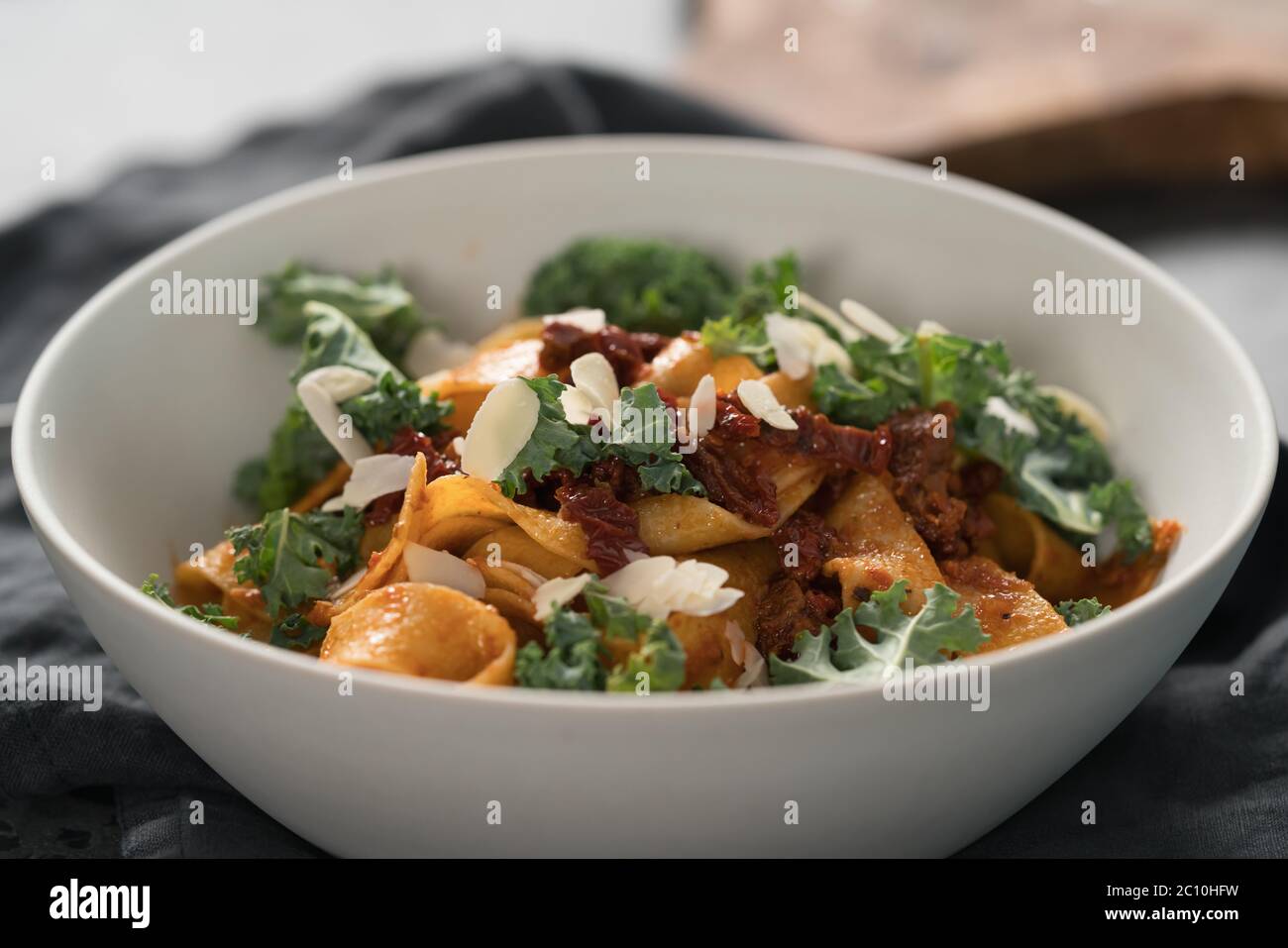 fettuccine pasta with sun-dried tomatoes, almond flakes and kale leaves Stock Photo