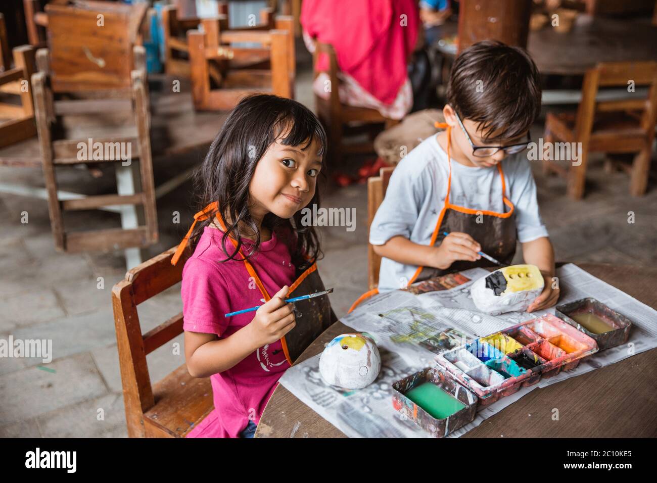 little girl smiles looking at the camera while painting handicrafts in ...