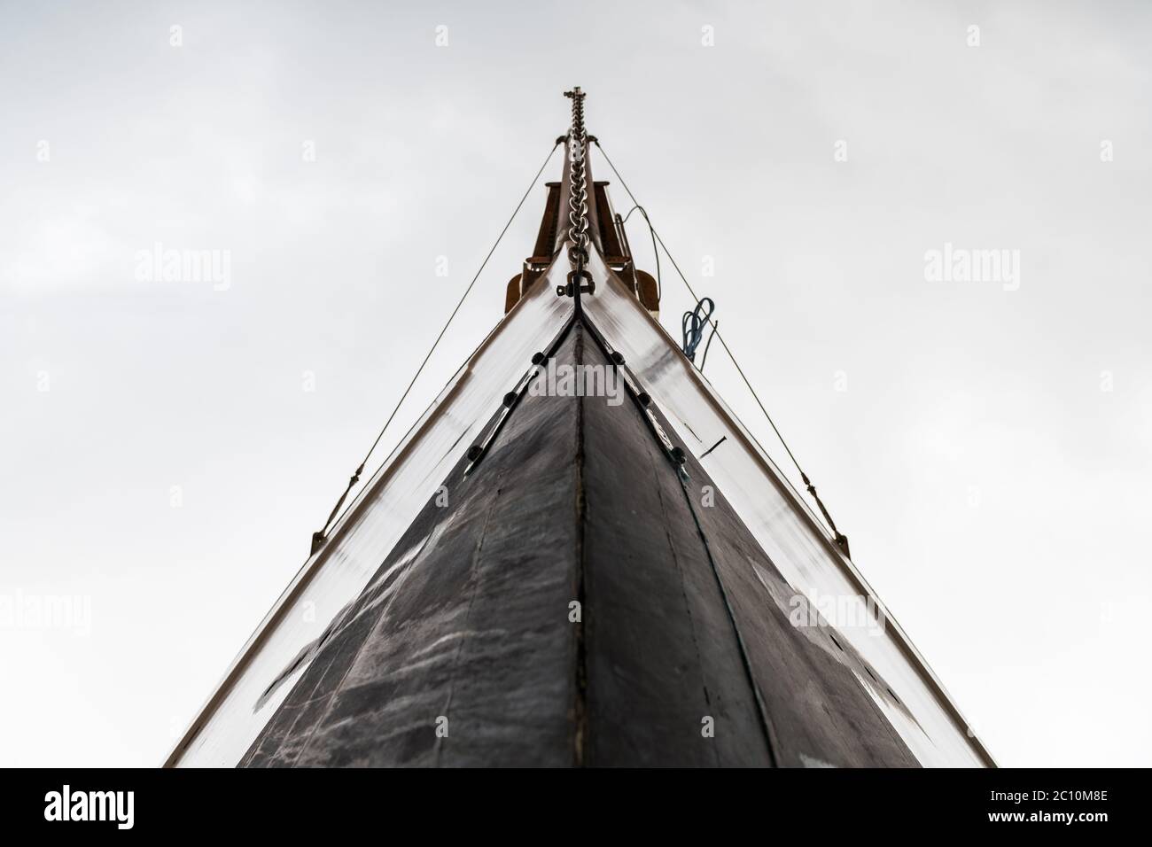 Low angle-view of the bow of a wooden luxury sail boat against a cloudy sky. Stock Photo