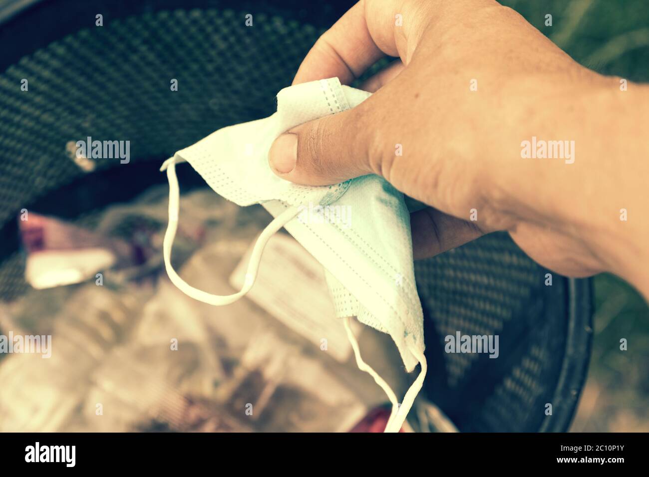 Man throwing face masks into trash in park. Man throwing used surgical