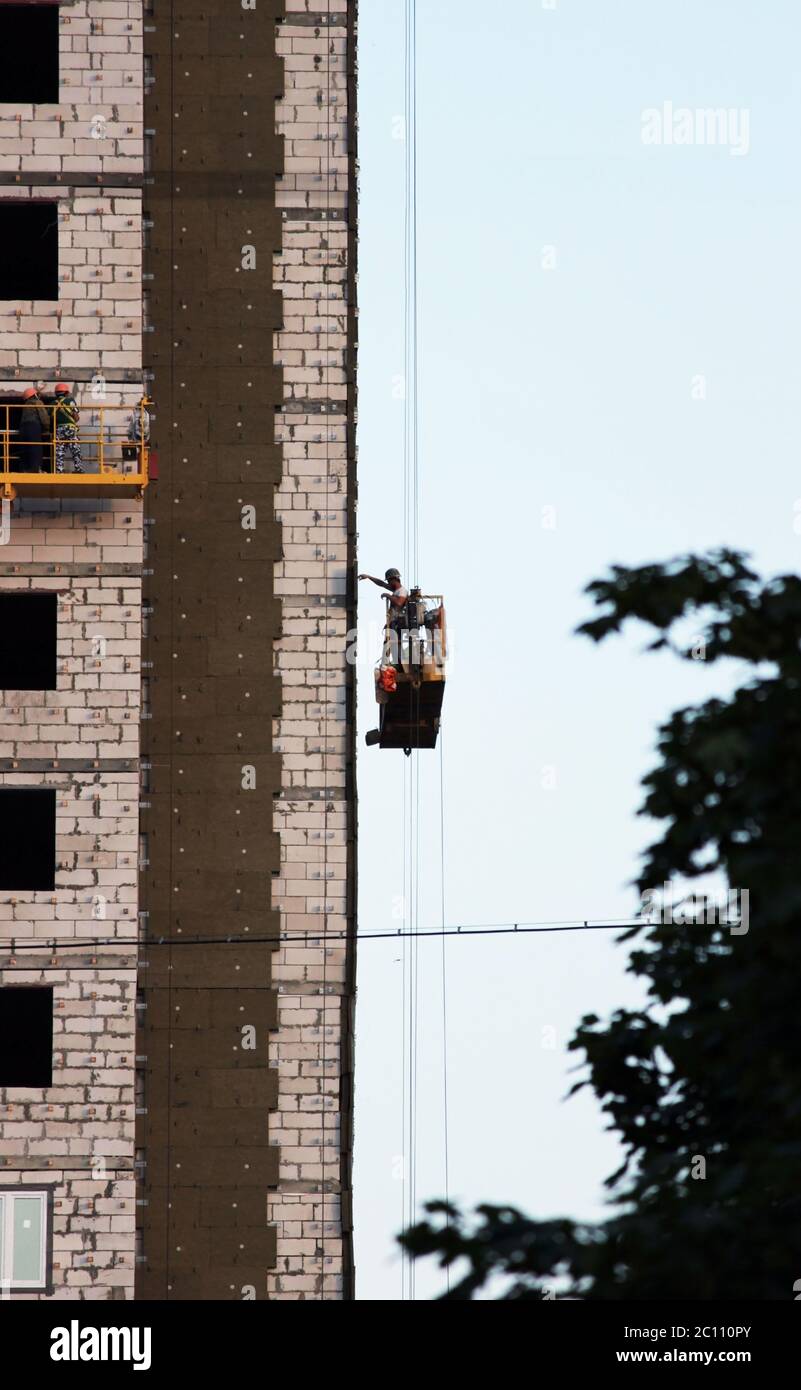 construction suspended cradle with worker on a newly built high-rise building Stock Photo