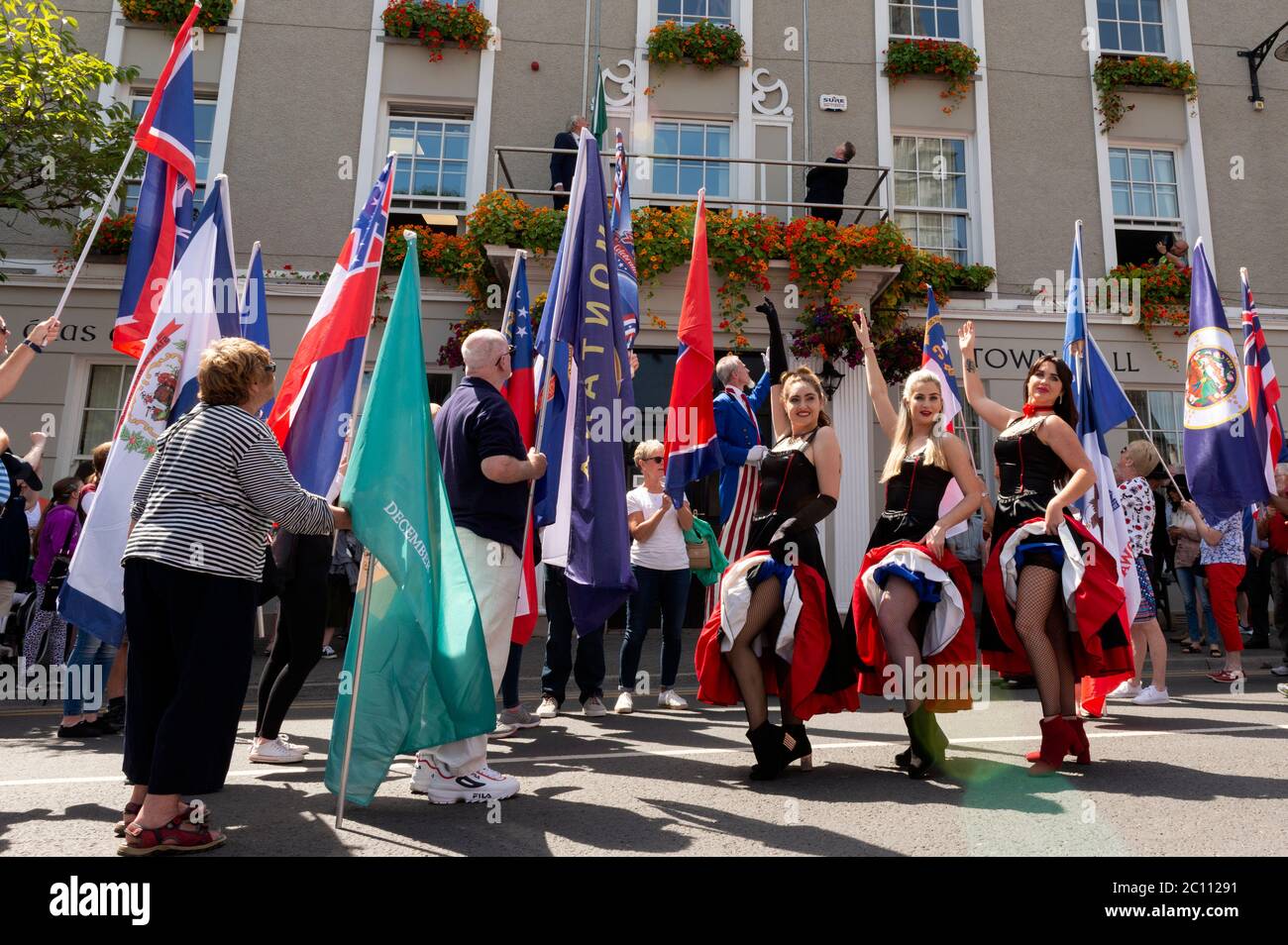 People with flags and burlesque dancers artists performers on street for the 4th of July Independence Day Parade and celebrations in Killarney County Kerry Ireland Stock Photo
