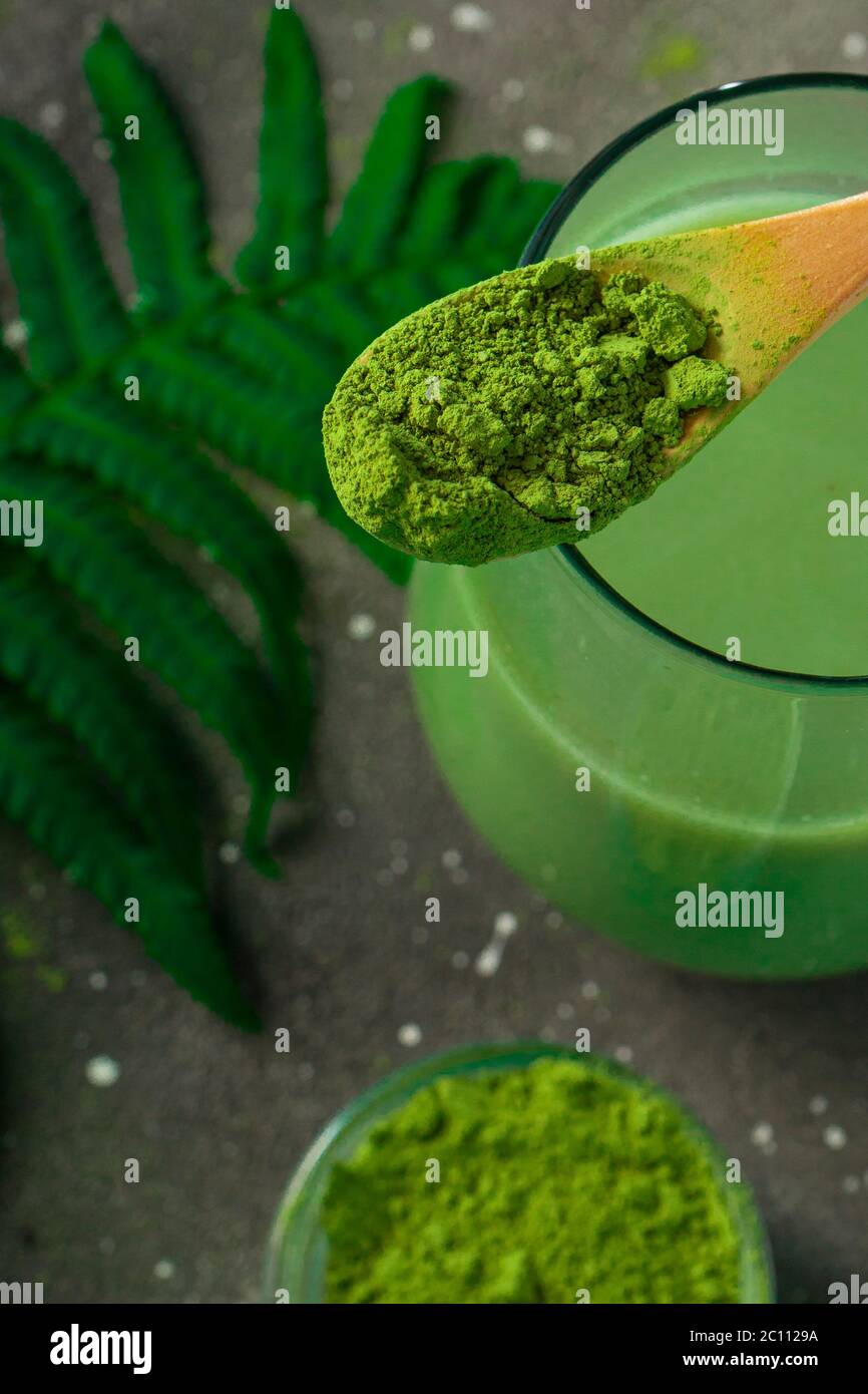 selective focus, Japanese green matcha tea with milk, with a wooden spoon and foliage on a dark background Stock Photo