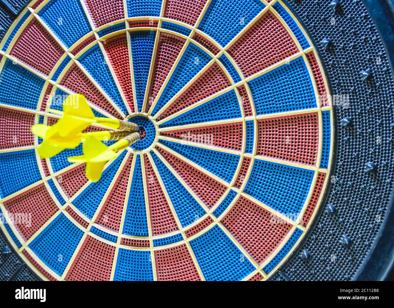 Dart in bulls eye of blurred dartboard Stock Photo