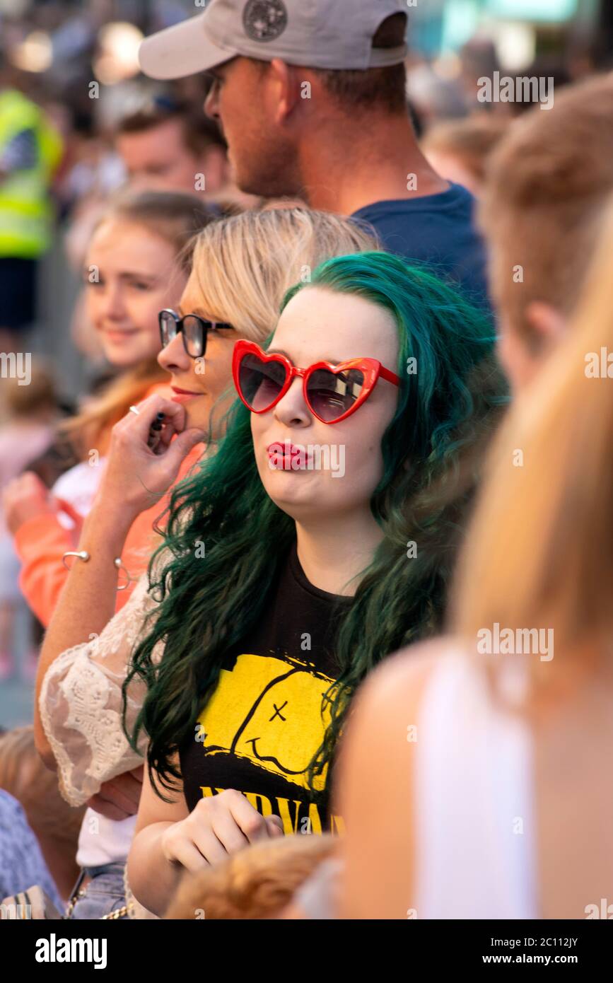 Flamboyant young woman with green coloured hair is among the crowd of people attending the street celebrations for 4th of July Parade and the Independence Day celebrations in Killarney, County Kerry, Ireland Stock Photo