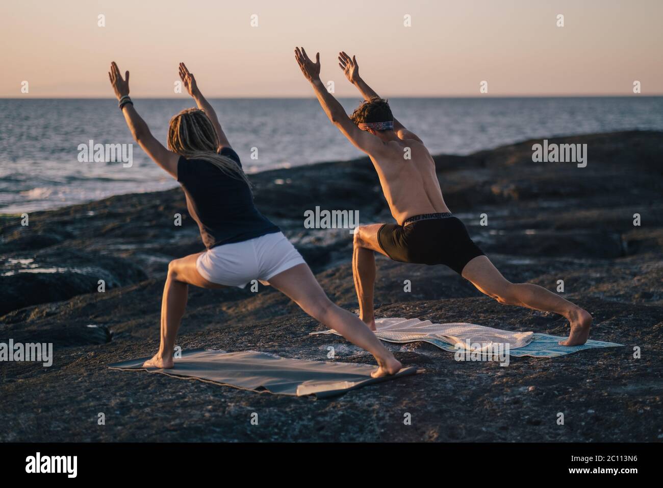 fitness, sport, and lifestyle concept - couple making yoga exercises on beach Stock Photo