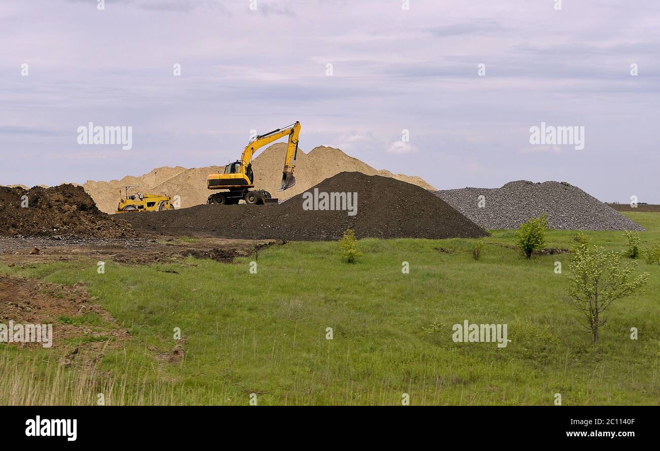 Yellow excavator working digging in sand quarry Stock Photo