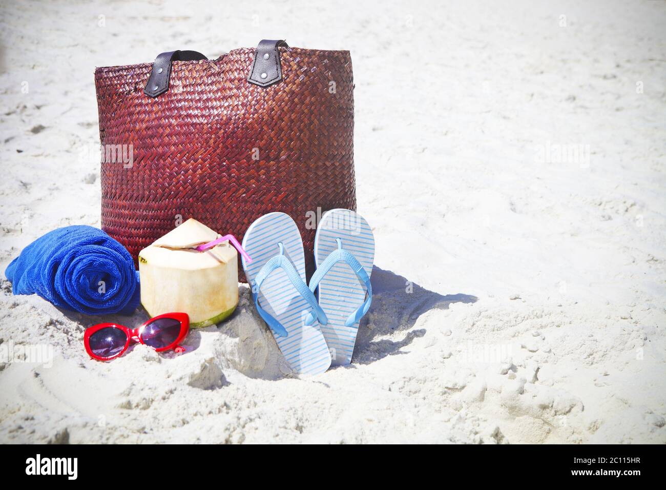 Flip flops, sunglasses, beach towel with beach bag and coconut cocktail Stock Photo