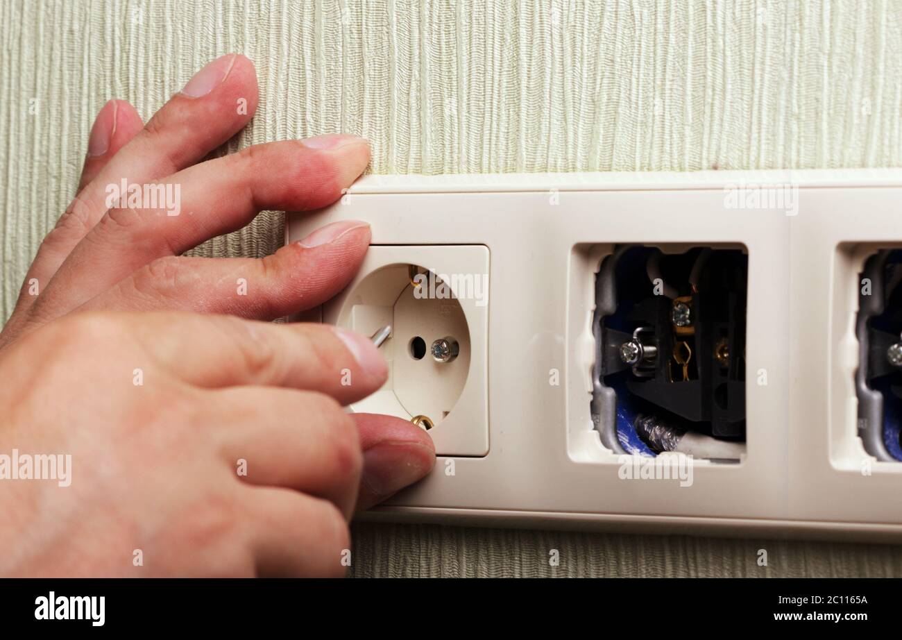 Worker man electrician is repairing damaged sockets in the apartment, installation of new  closeup Stock Photo