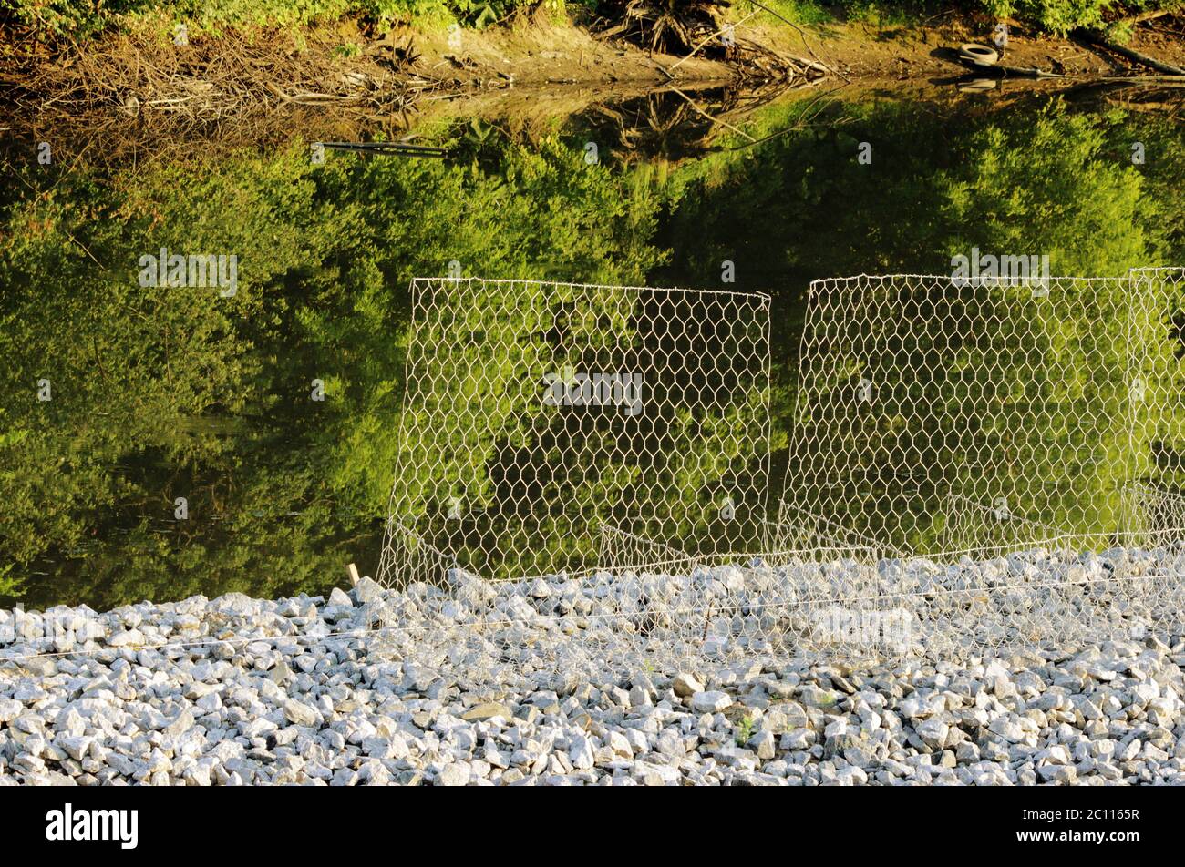 metal protective mesh near the canal with water protects the shedding of gravel roads Stock Photo