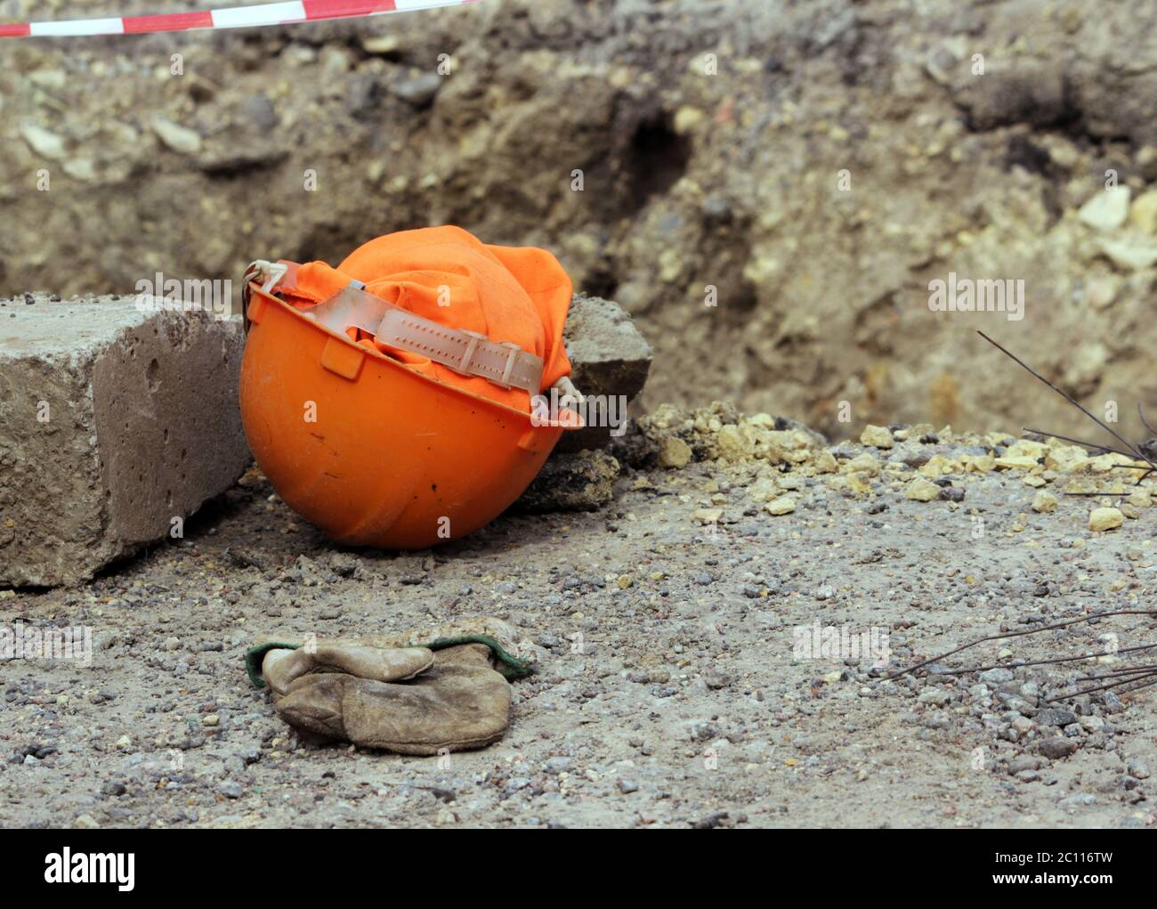 orange construction helmet and mitten lies on the edge of the ditch