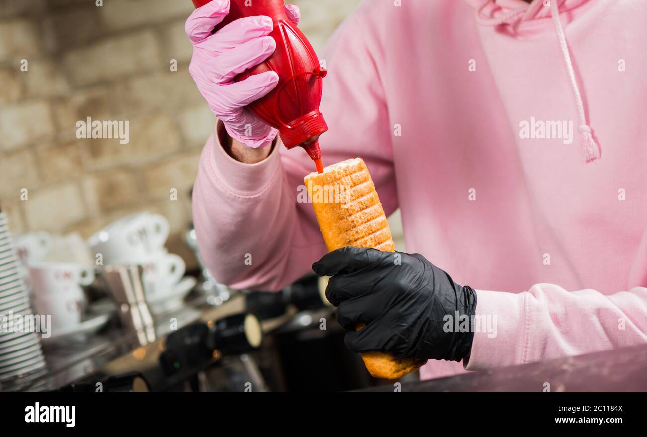 bartender adding ketchup sauce in french hot dog with grill sausage Stock Photo