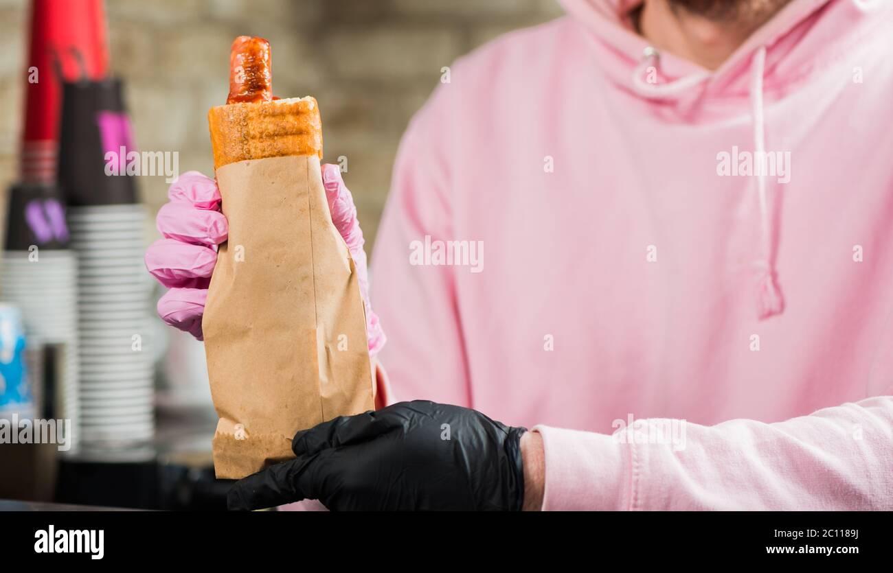 bartender holding french hot dog with grill sausage in paper package Stock Photo