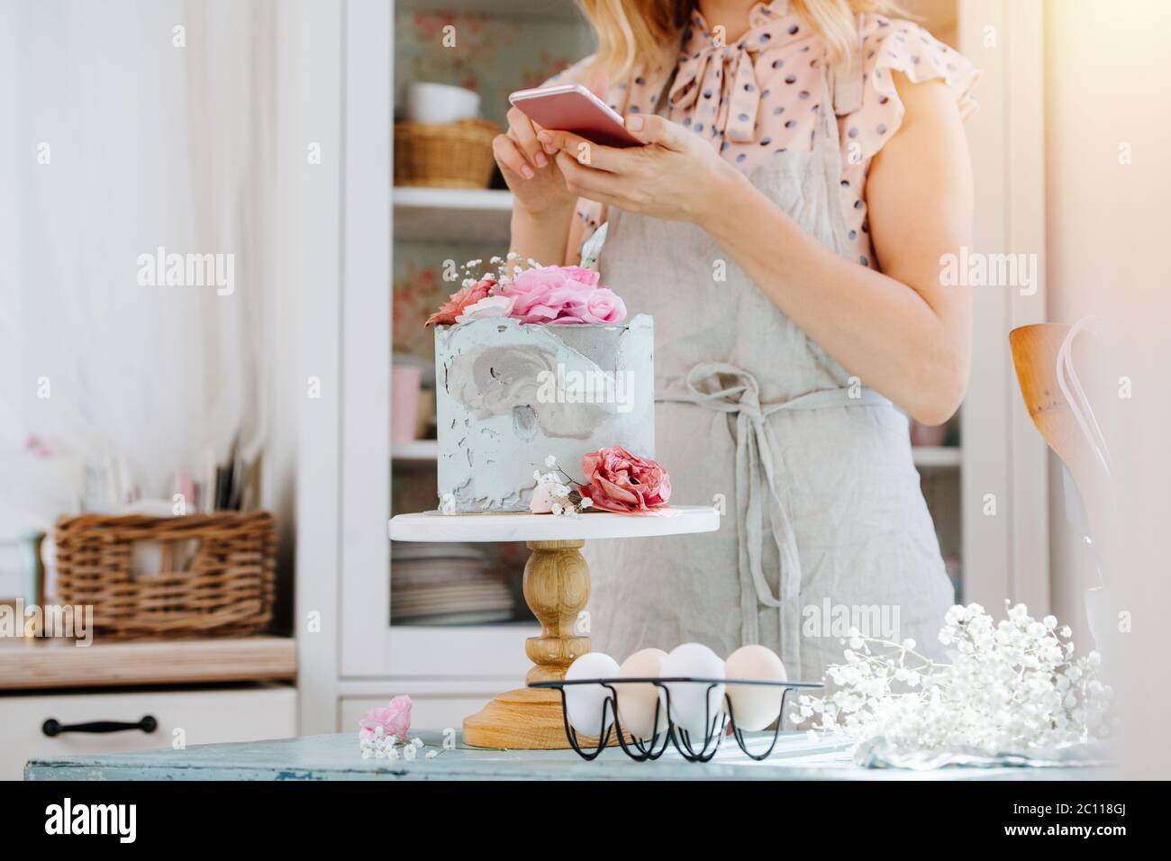 Young housewife texing, taking short break from baking sweet cake. Stock Photo