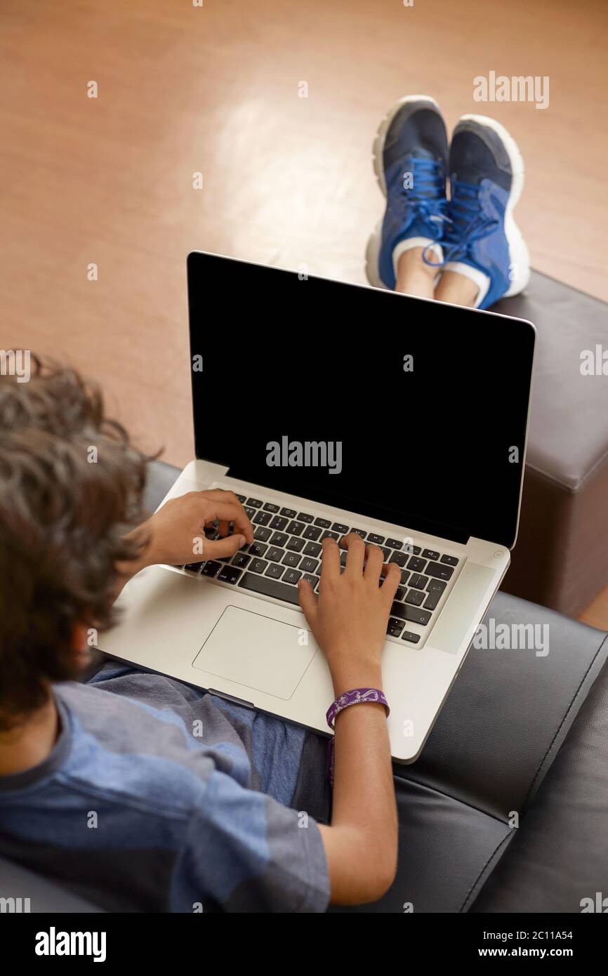 Latino Boy Sitting on Sofa with Laptop Computer Stock Photo