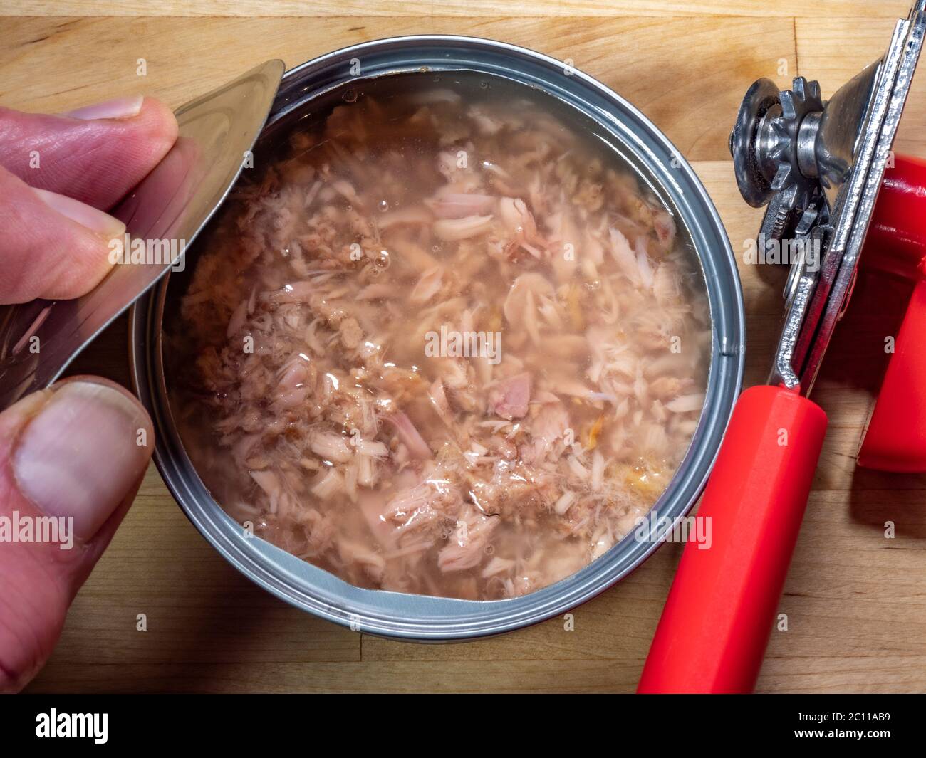 An open can and hand holding a can opener Stock Photo - Alamy