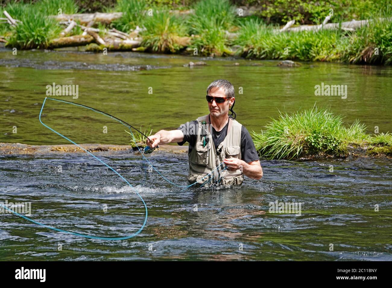 A trout fisherman fly fishing for rainbow trout with a fly rod on the