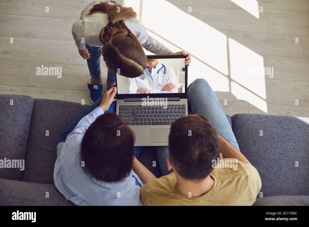 Doctor online. Happy family talks consults with a doctor using a laptop while at home. Stock Photo