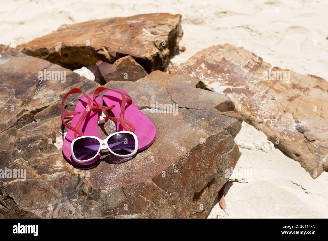 Pink flip flop shoes and Fashion sunglasses on the rock of beach ...