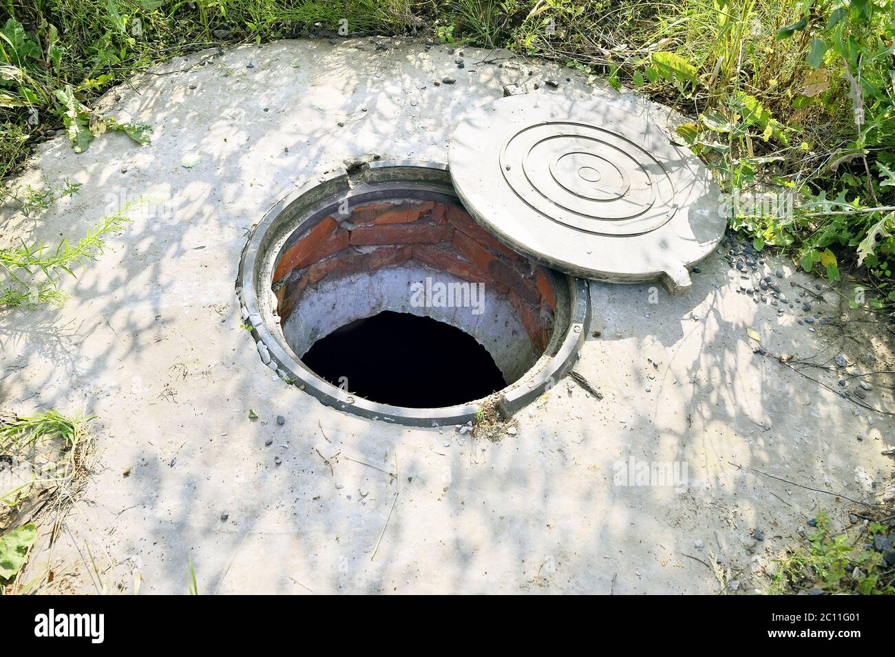 Concrete cesspit with an open hatch on the ground in the summer Stock Photo