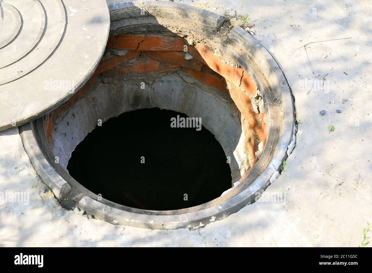 Concrete cesspit with an open hatch on the ground in the summer Stock Photo