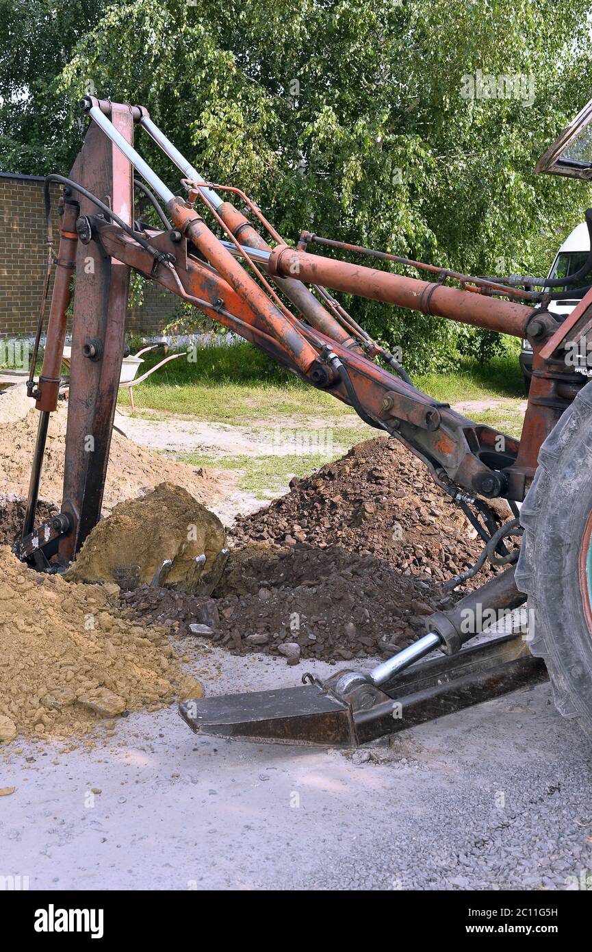 Excavator bucket digging a trench in the dirt ground Stock Photo