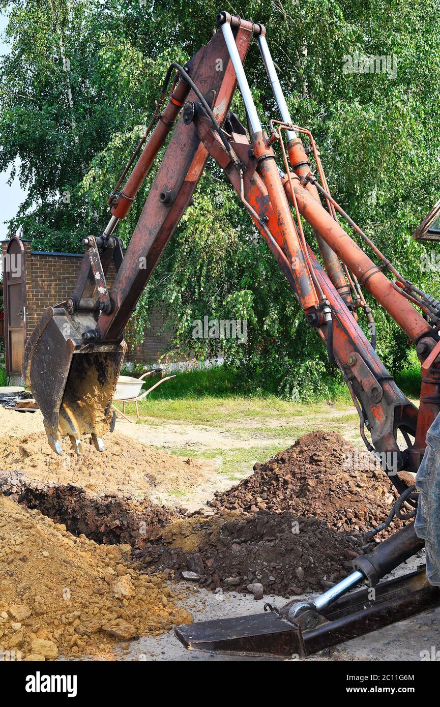 Excavator bucket digging a trench in the dirt ground Stock Photo