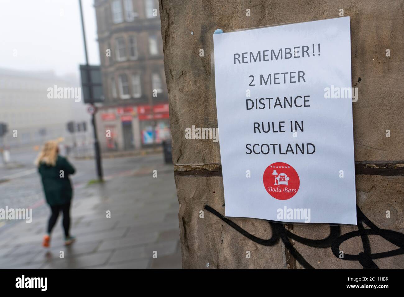 Edinburgh, Scotland, UK. 13 June 2020. On a foggy wet Saturday afternoon the streets of Edinburgh city centre remain very quiet and shops and businesses remain closed. Lockdown is expected to be relaxed next month.  Social distancing remains 2m in Scotland warning sign on pub wall. Iain Masterton/Alamy Live News Stock Photo