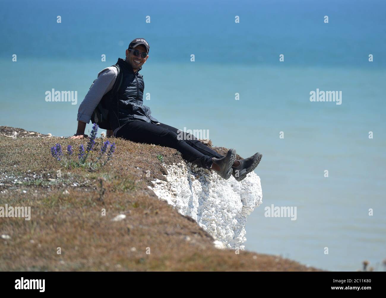 Birling Gap, East Sussex, UK. 13th June, 2020. Tourists get too close to the edge of the crumbling Seven Sisters white chalk cliffs on the Sussex Coast. The iconic cliffs tower up to 400ft above the English Channel. Credit: Peter Cripps/Alamy Live News Stock Photo