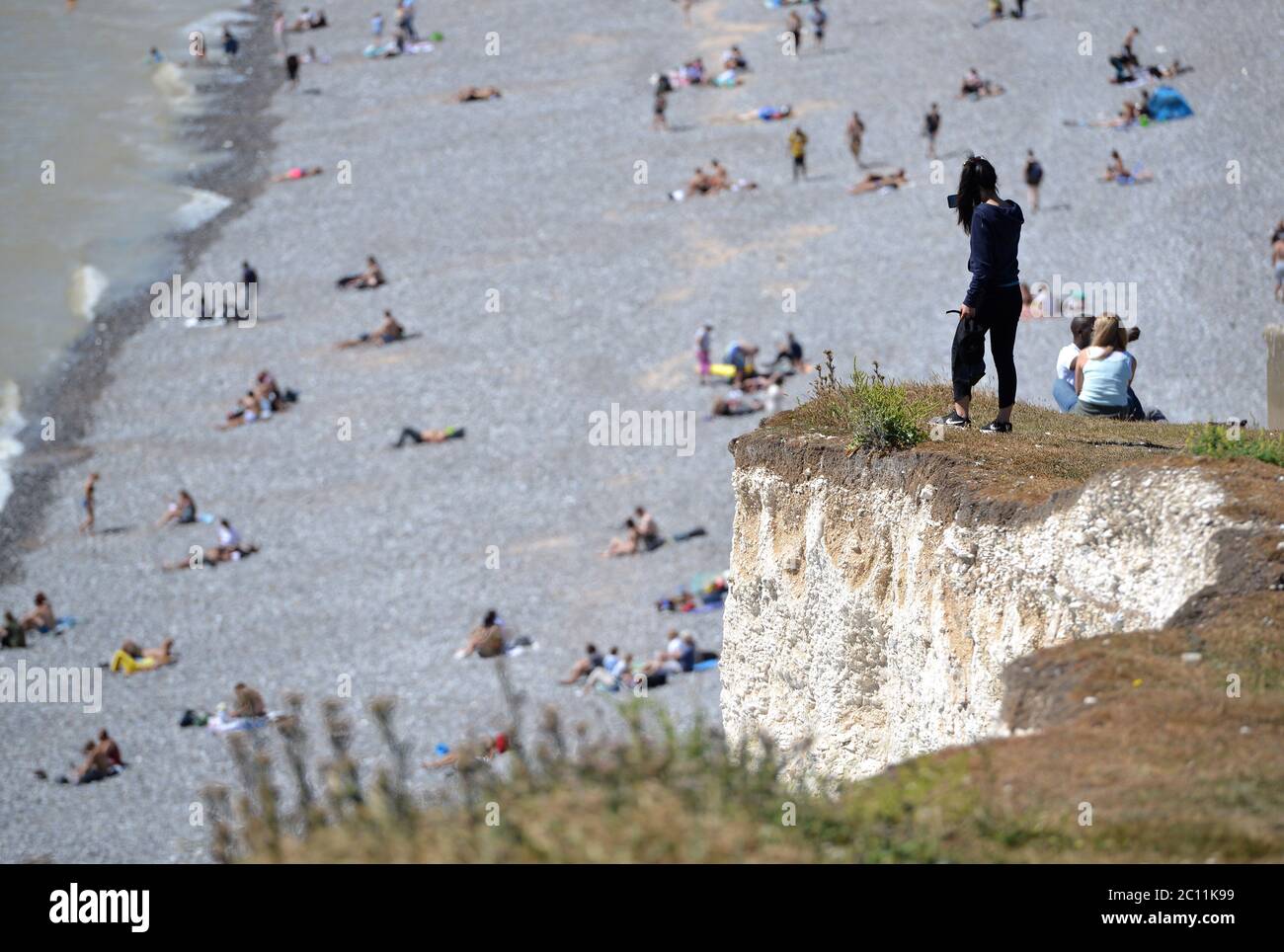 Birling Gap, East Sussex, UK. 13th June, 2020. Tourists get too close to the edge of the crumbling Seven Sisters white chalk cliffs on the Sussex Coast. The iconic cliffs tower up to 400ft above the English Channel. Credit: Peter Cripps/Alamy Live News Stock Photo