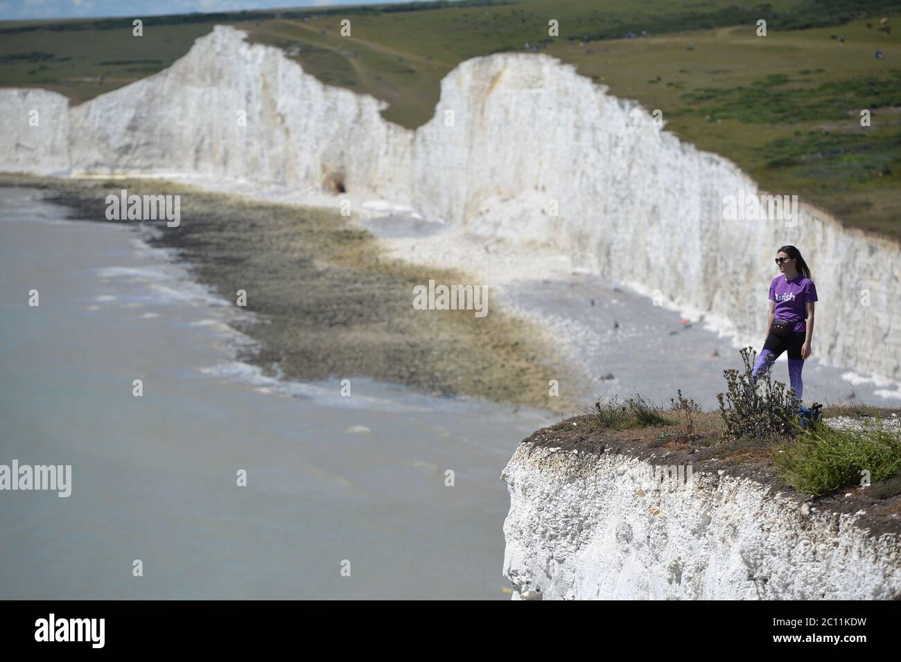 Birling Gap, East Sussex, UK. 13th June, 2020. Tourists get too close to the edge of the crumbling Seven Sisters white chalk cliffs on the Sussex Coast. The iconic cliffs tower up to 400ft above the English Channel. Credit: Peter Cripps/Alamy Live News Stock Photo